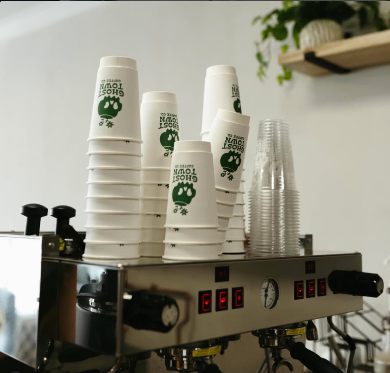 Stacks of Ghost Town Coffee Co. branded cups hanging under the espresso machine